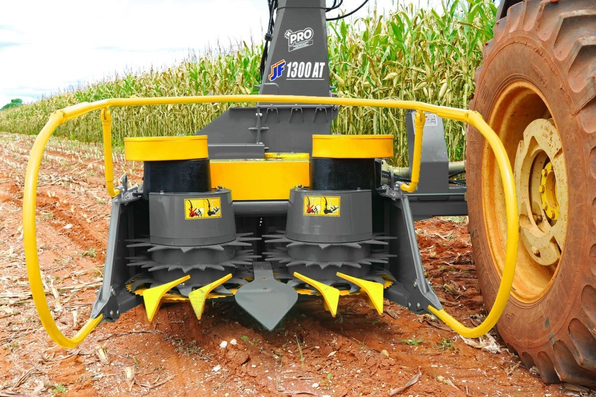 A tractor is cutting grass in a field with a machine attached to it.