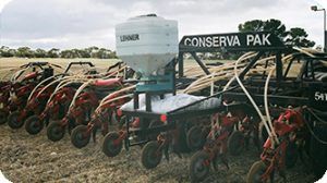A row of conserve pak tractors are lined up in a field