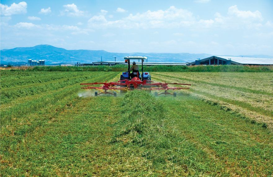 A man is driving a tractor through a field of grass.