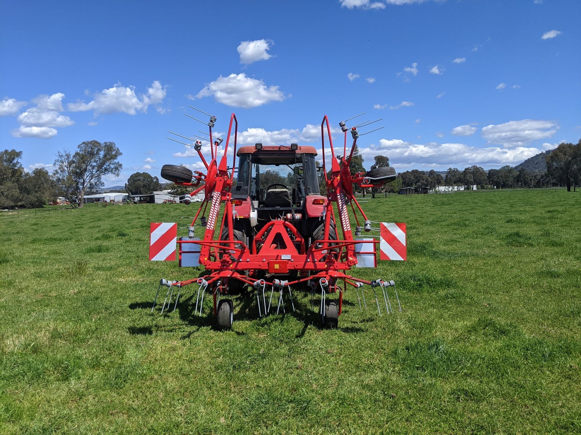 A red tractor is parked in a grassy field.