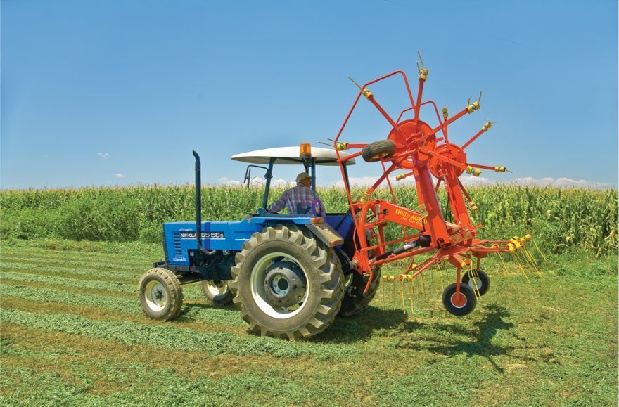 A man is driving a blue tractor in a field.