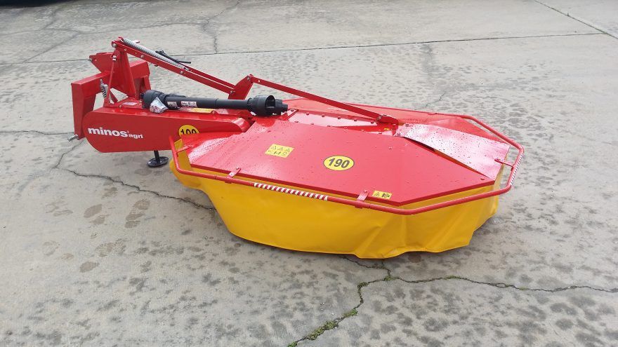 A red and yellow mower is sitting on a concrete surface.