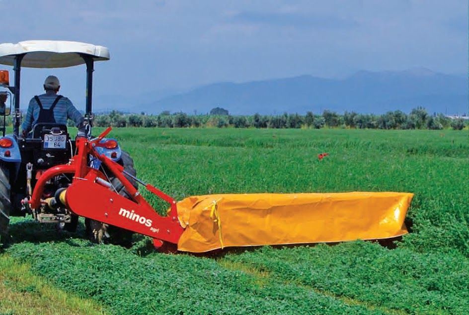 A man is driving a tractor through a grassy field.