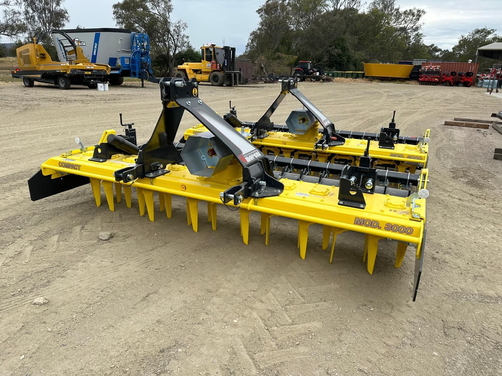 A tractor is plowing a field with a yellow and black machine.