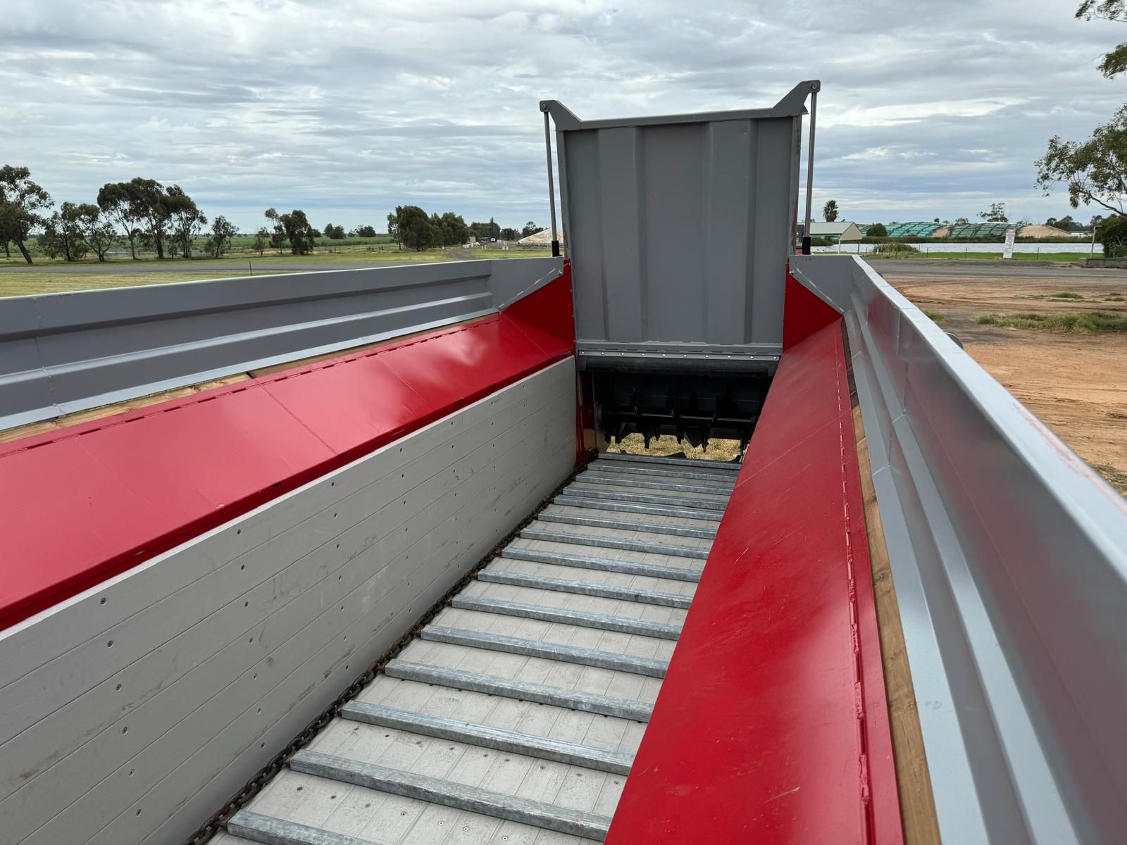 A red and gray container with a conveyor belt going through it