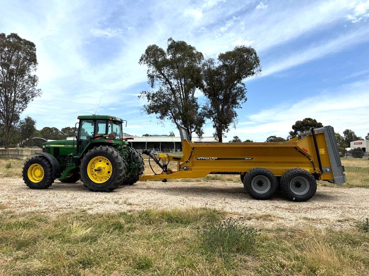 A john deere tractor is pulling a yellow trailer.
