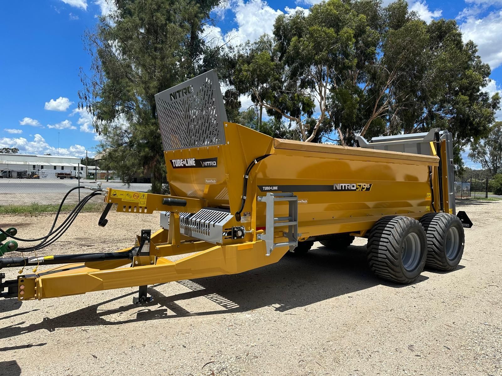 A yellow manure spreader with the word nitro on it