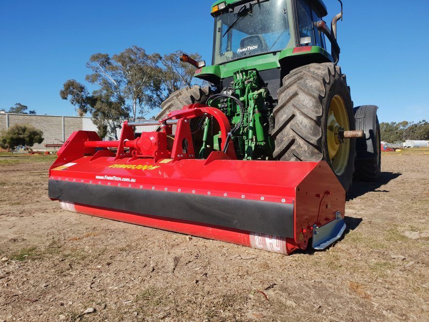 A green and red tractor is parked in a field