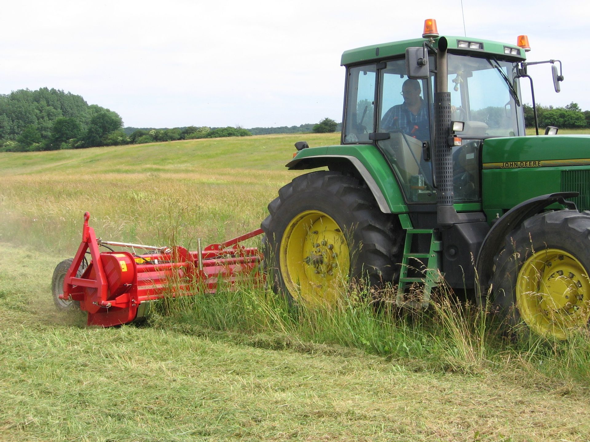 A john deere tractor is cutting grass in a field