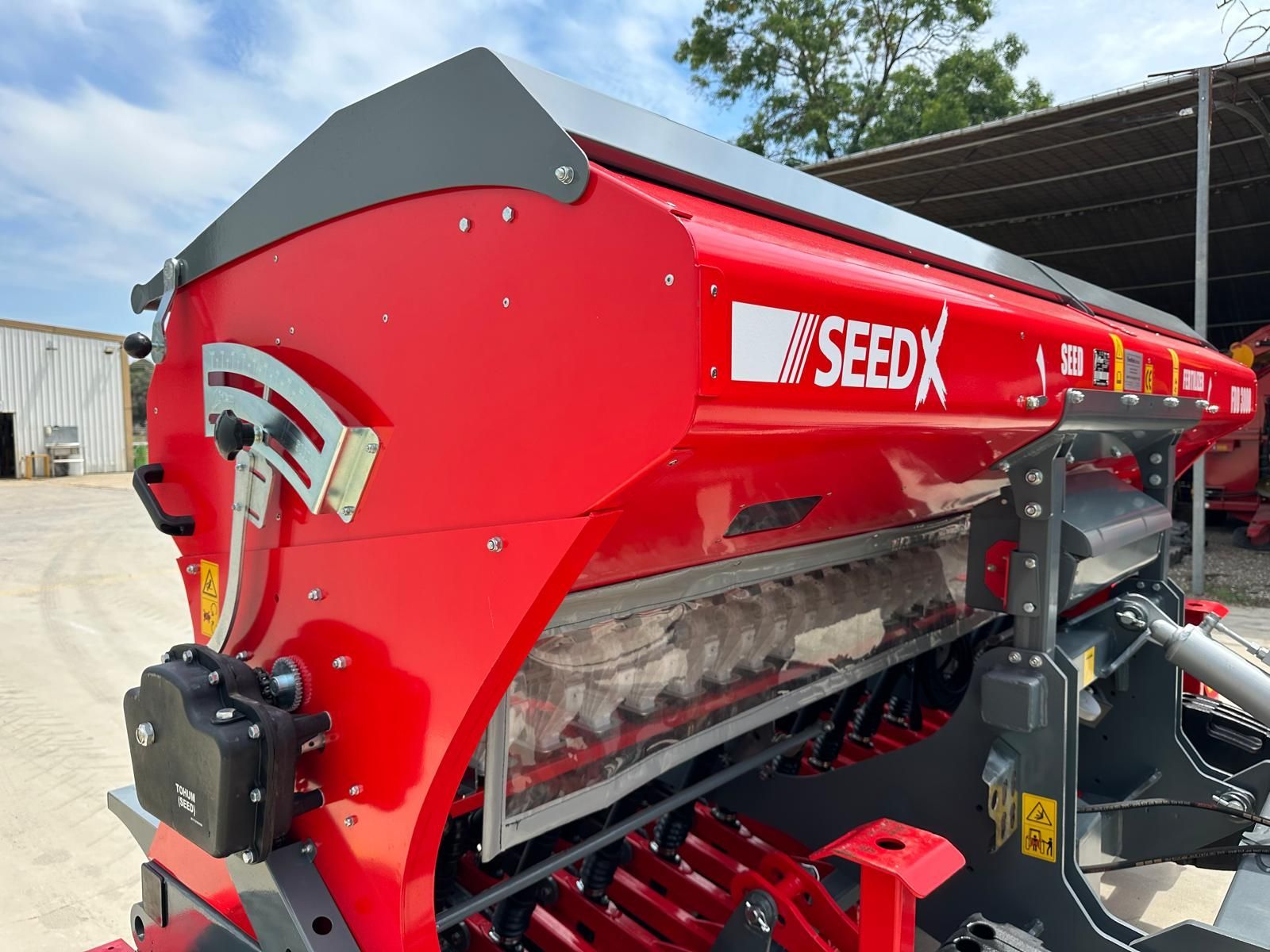 A red seed spreader is parked in front of a building.