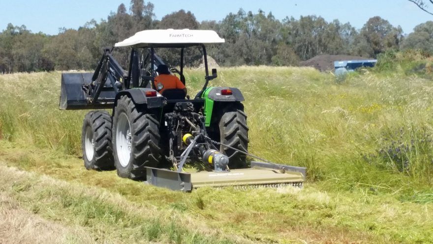 A man is driving a tractor through a grassy field.