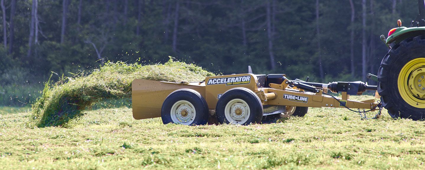 A tractor is cutting grass in a field with a machine attached to it.