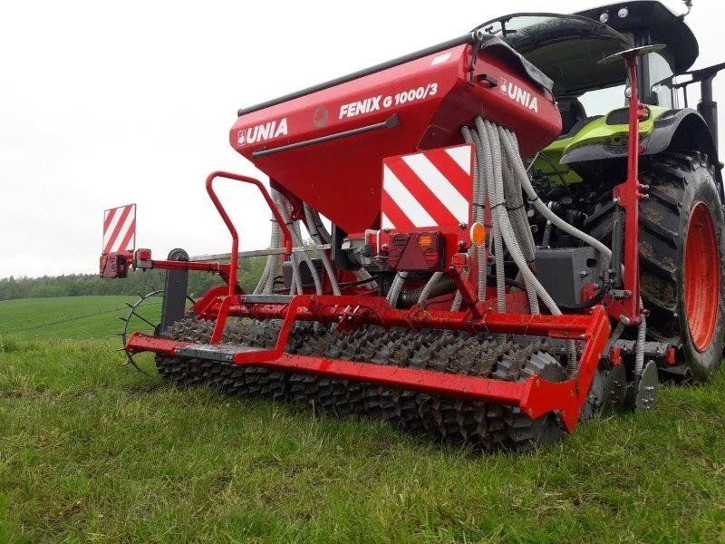 A red and white tractor is parked in a grassy field.