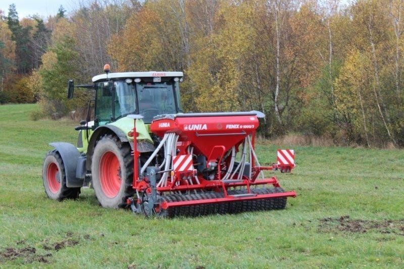 A tractor is driving through a grassy field.
