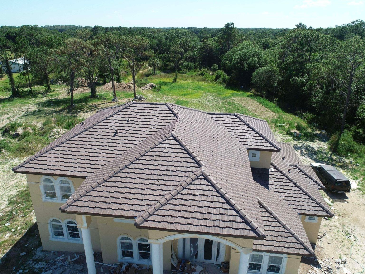 An aerial view of a house with a tile roof surrounded by trees.