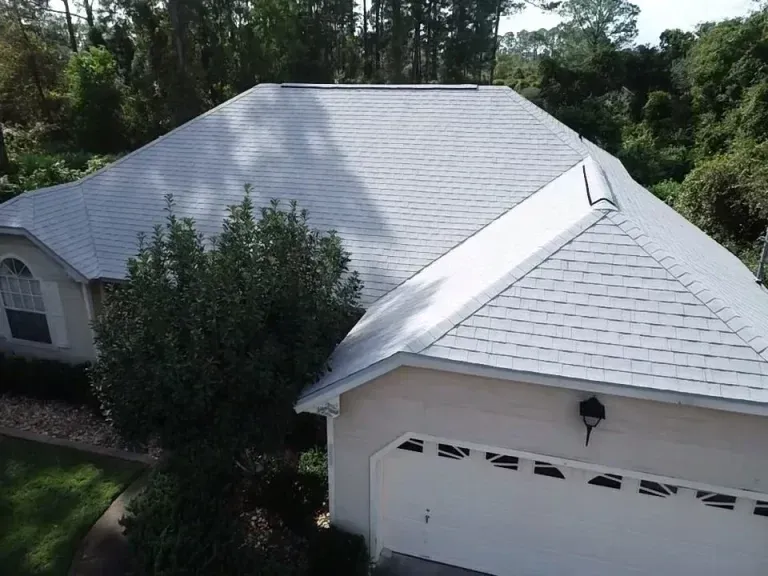 A man is standing on top of a roof holding a clipboard and giving a thumbs up.