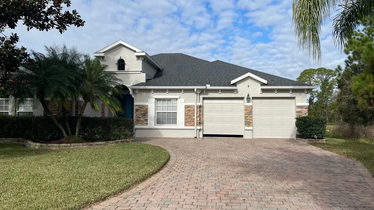 A white house with a gray roof and a driveway