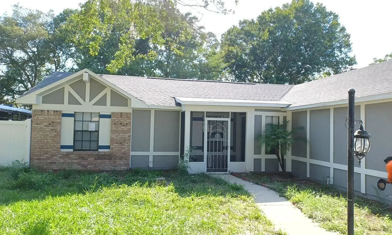 A house with a screened in porch and a walkway leading to it