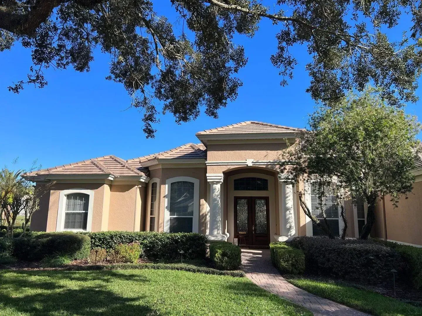 A house with a lush green lawn and trees in front of it