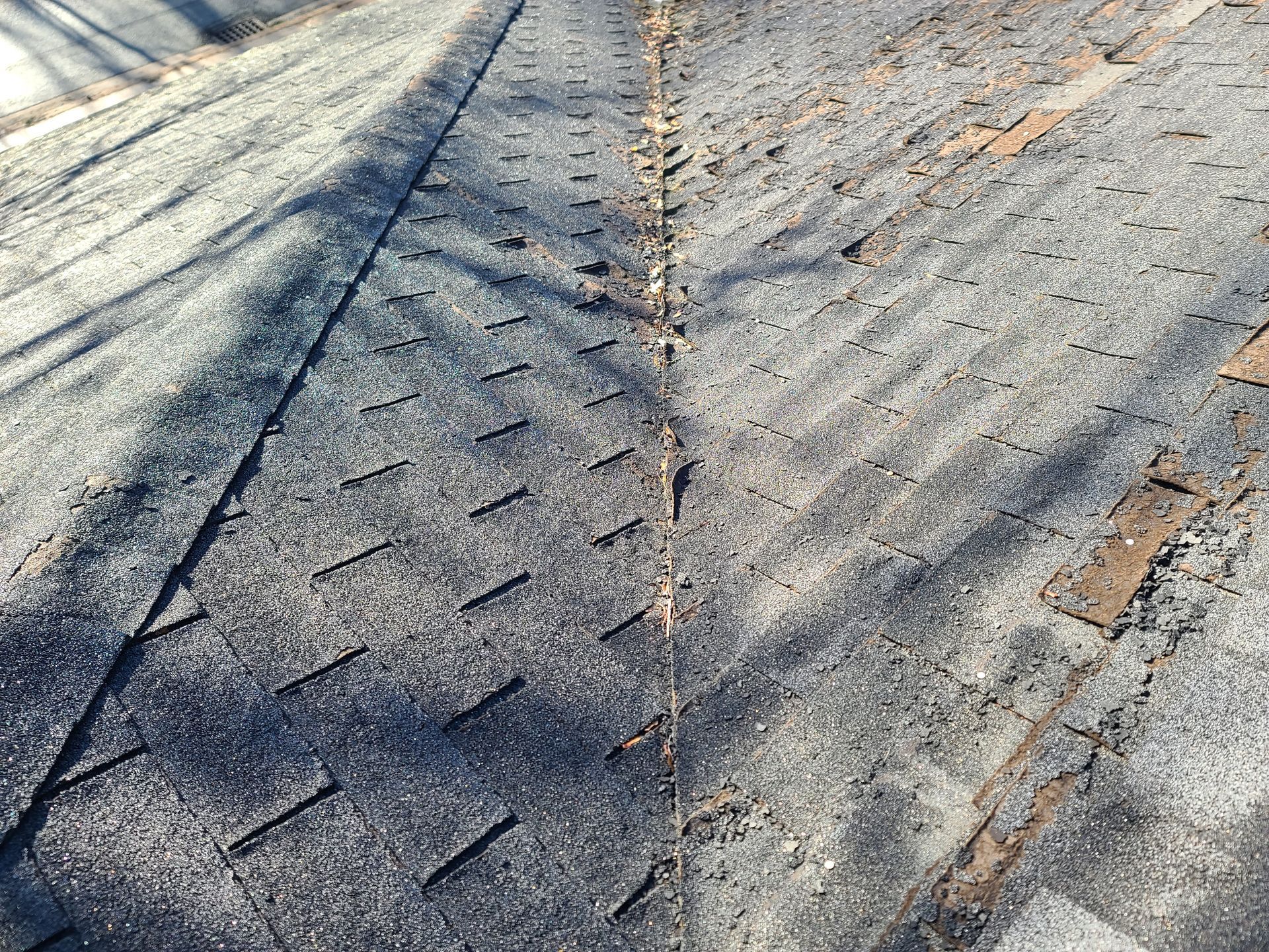 A close up of a roof that is aging with peeling shingles