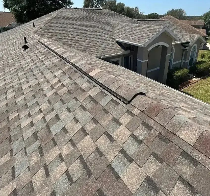 A man is standing on top of a roof holding a clipboard and giving a thumbs up.