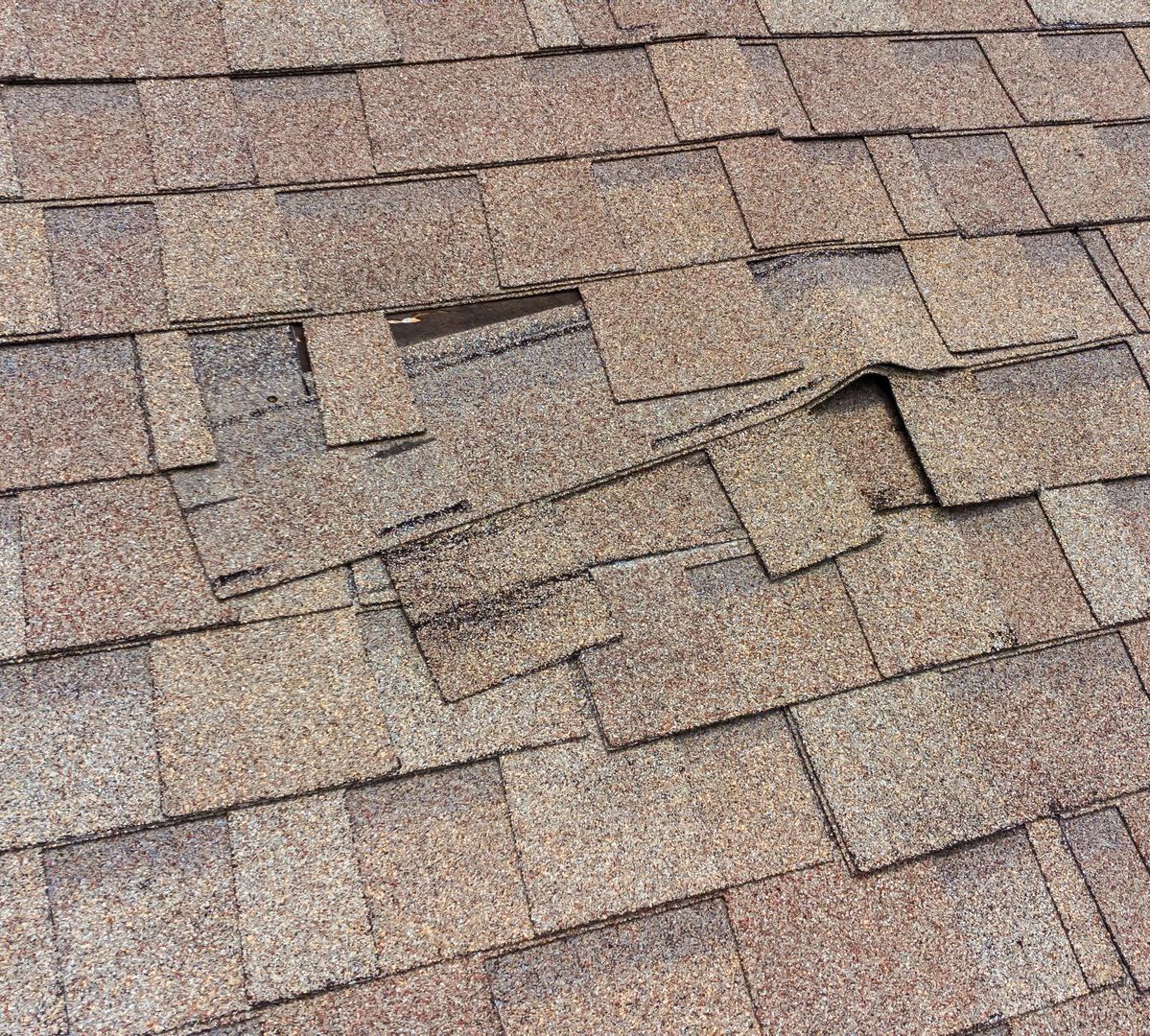 A close up of a roof with a lot of shingles missing.