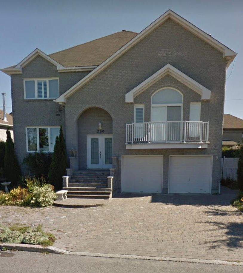 Une grande maison grise avec un balcon et des escaliers