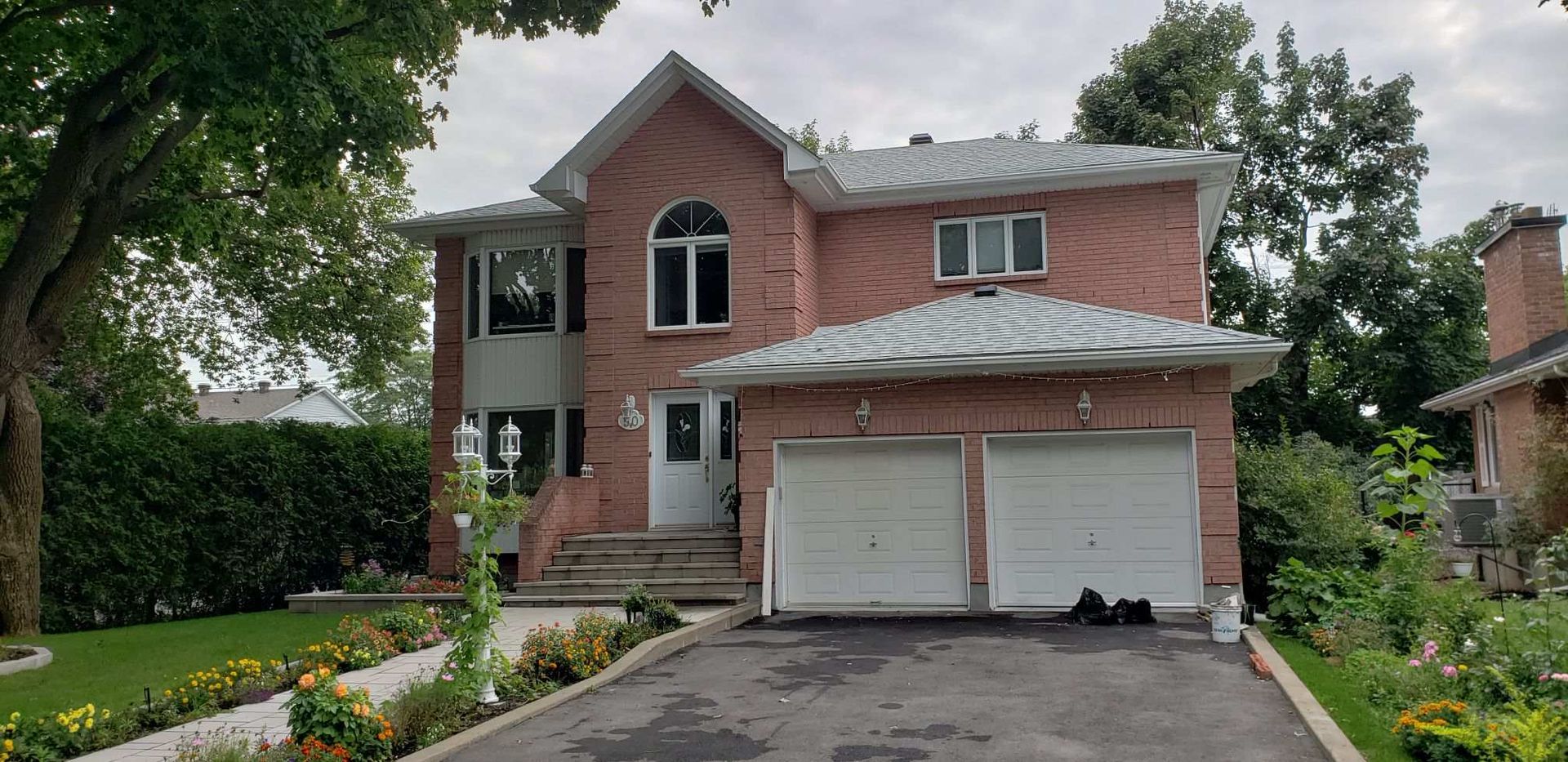 Une grande maison en brique avec deux portes de garage et une allée.