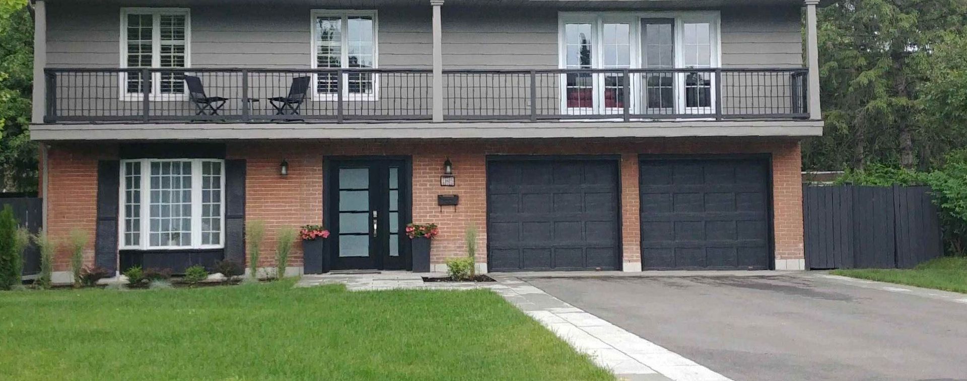 Une grande maison en brique avec deux garages et un balcon.