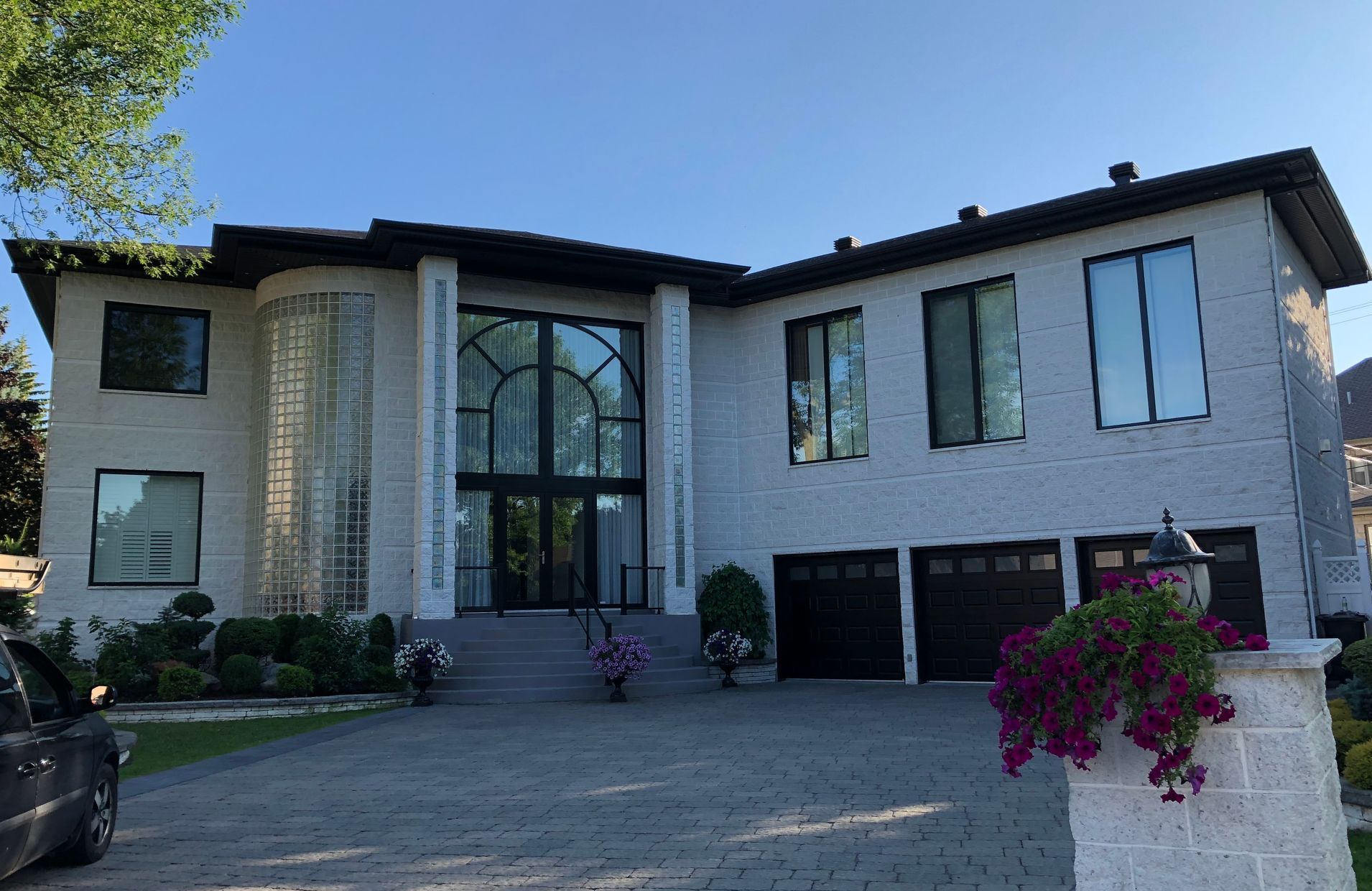 Une grande maison blanche avec une voiture garée devant.