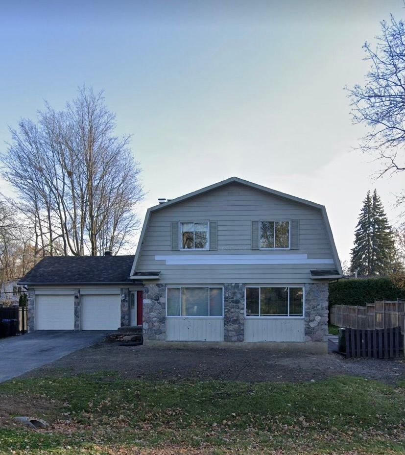 Une grande maison avec un toit de grange et deux garages