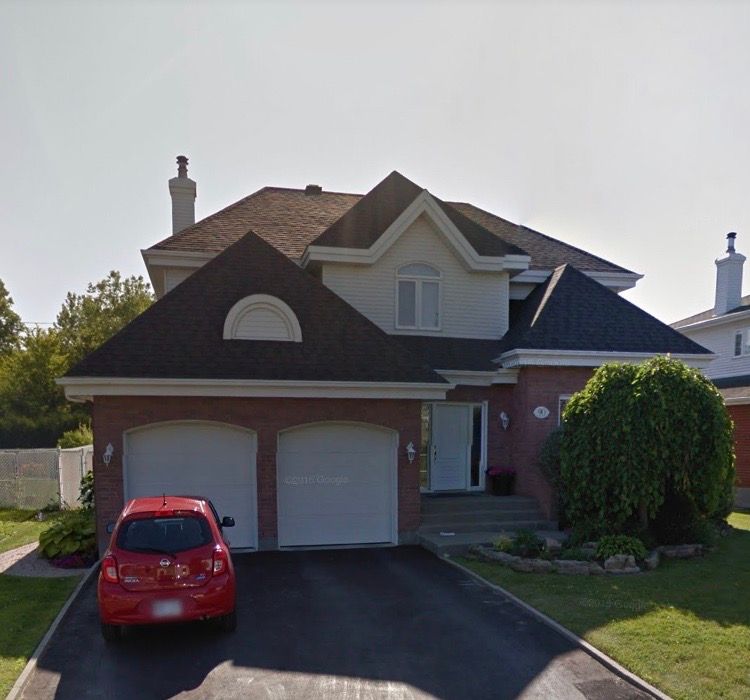 Une voiture rouge est garée devant une grande maison