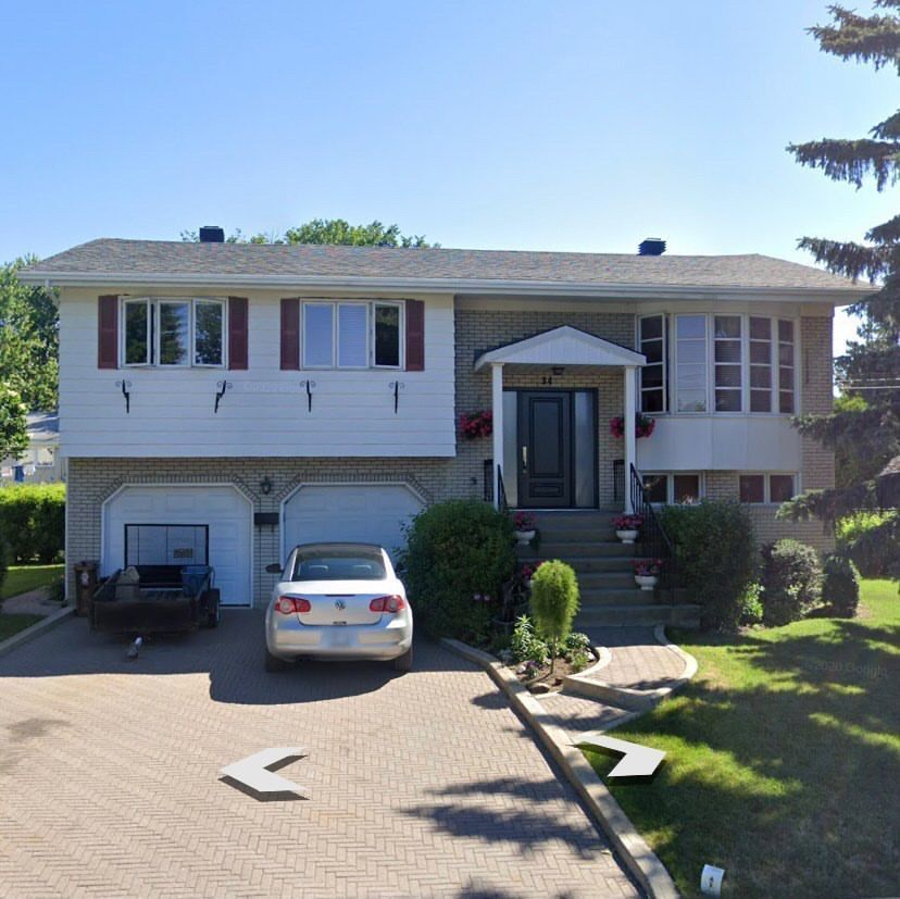 Une voiture blanche est garée devant une maison