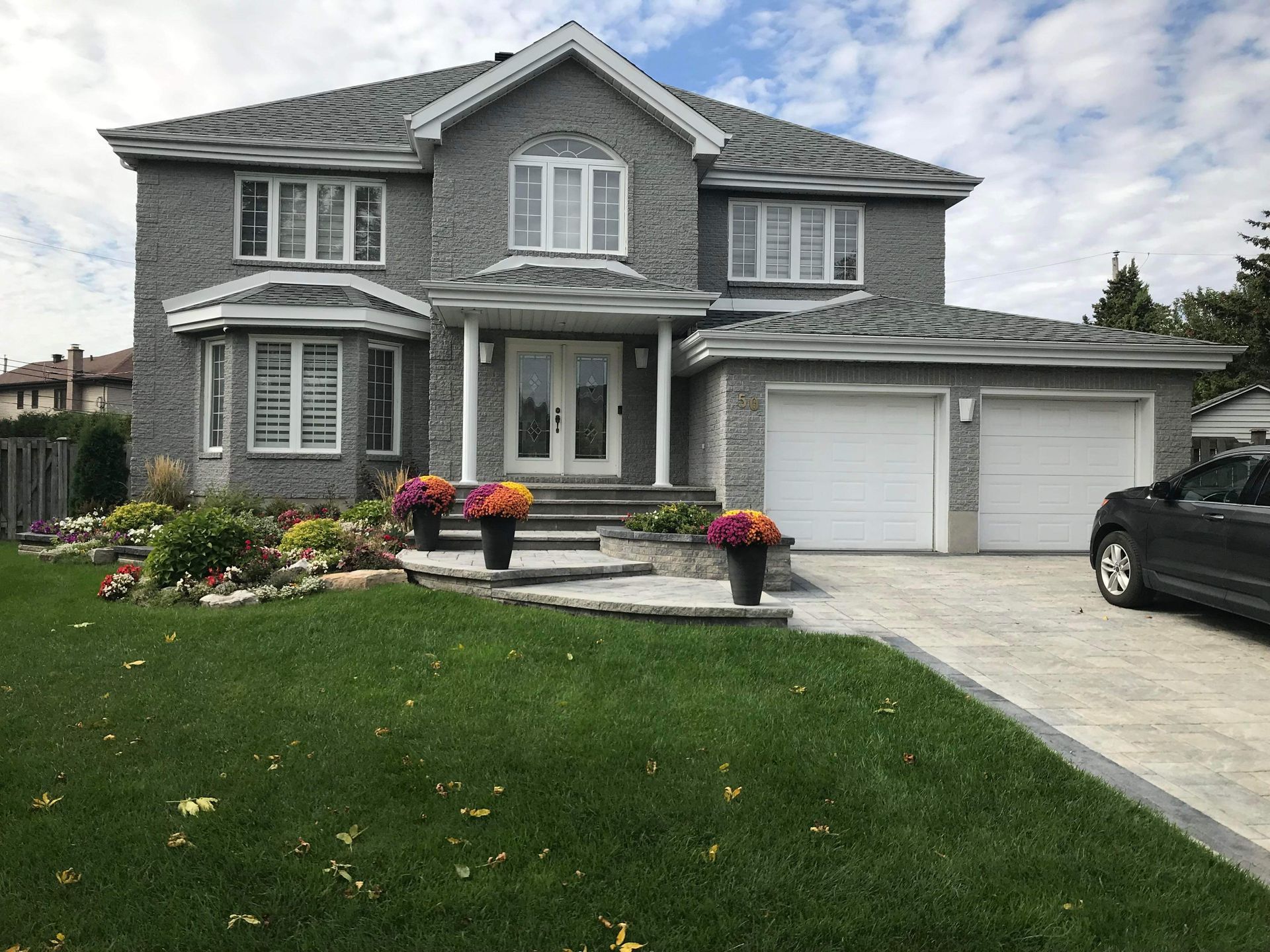 Une grande maison avec une voiture garée devant.