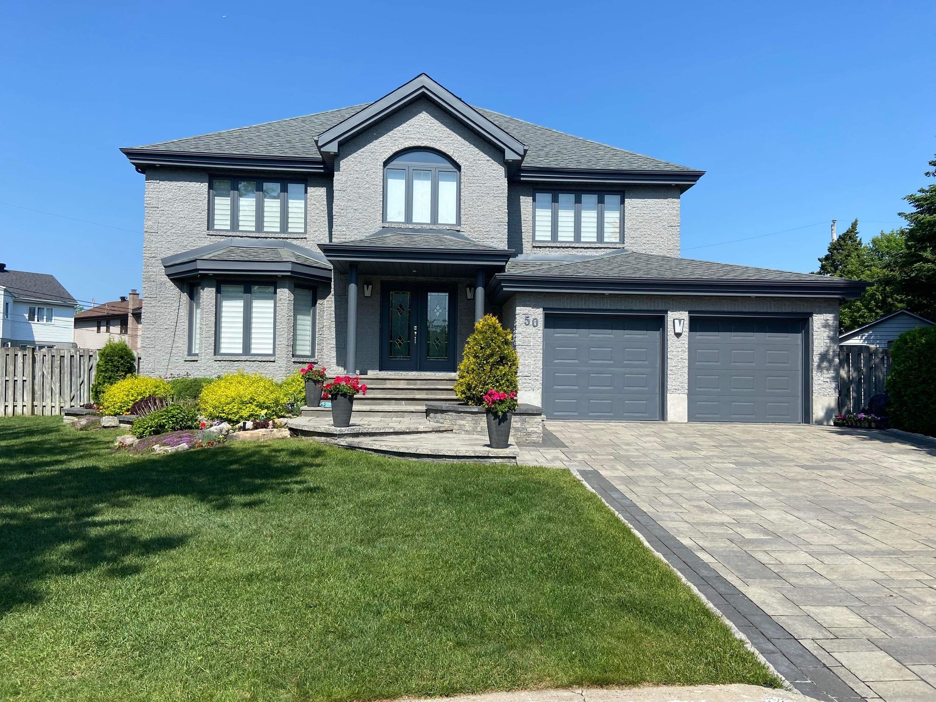 Une grande maison en brique avec deux garages et une pelouse verdoyante.