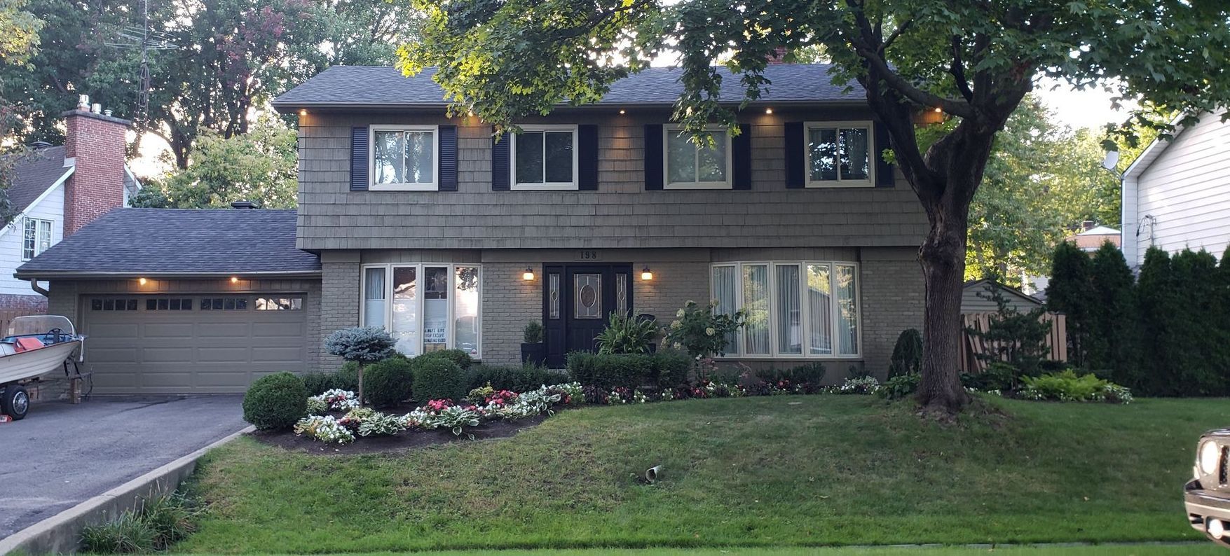 Une grande maison avec beaucoup de fenêtres et un arbre devant.