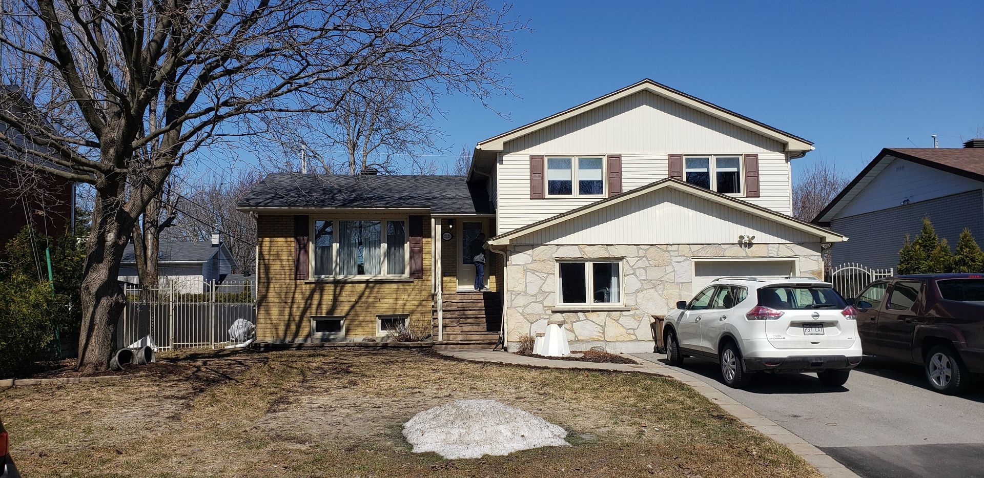 Une voiture blanche est garée devant une grande maison.