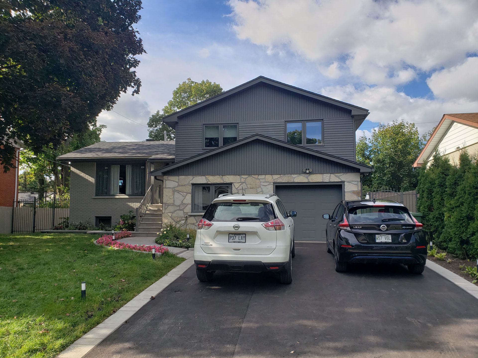 Deux voitures sont garées devant une grande maison.