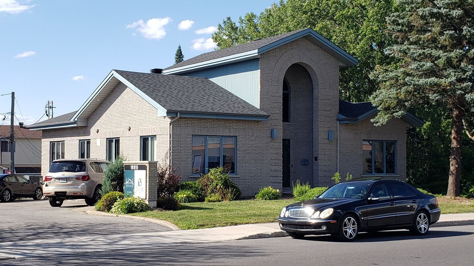 Une voiture noire est garée devant une grande maison.