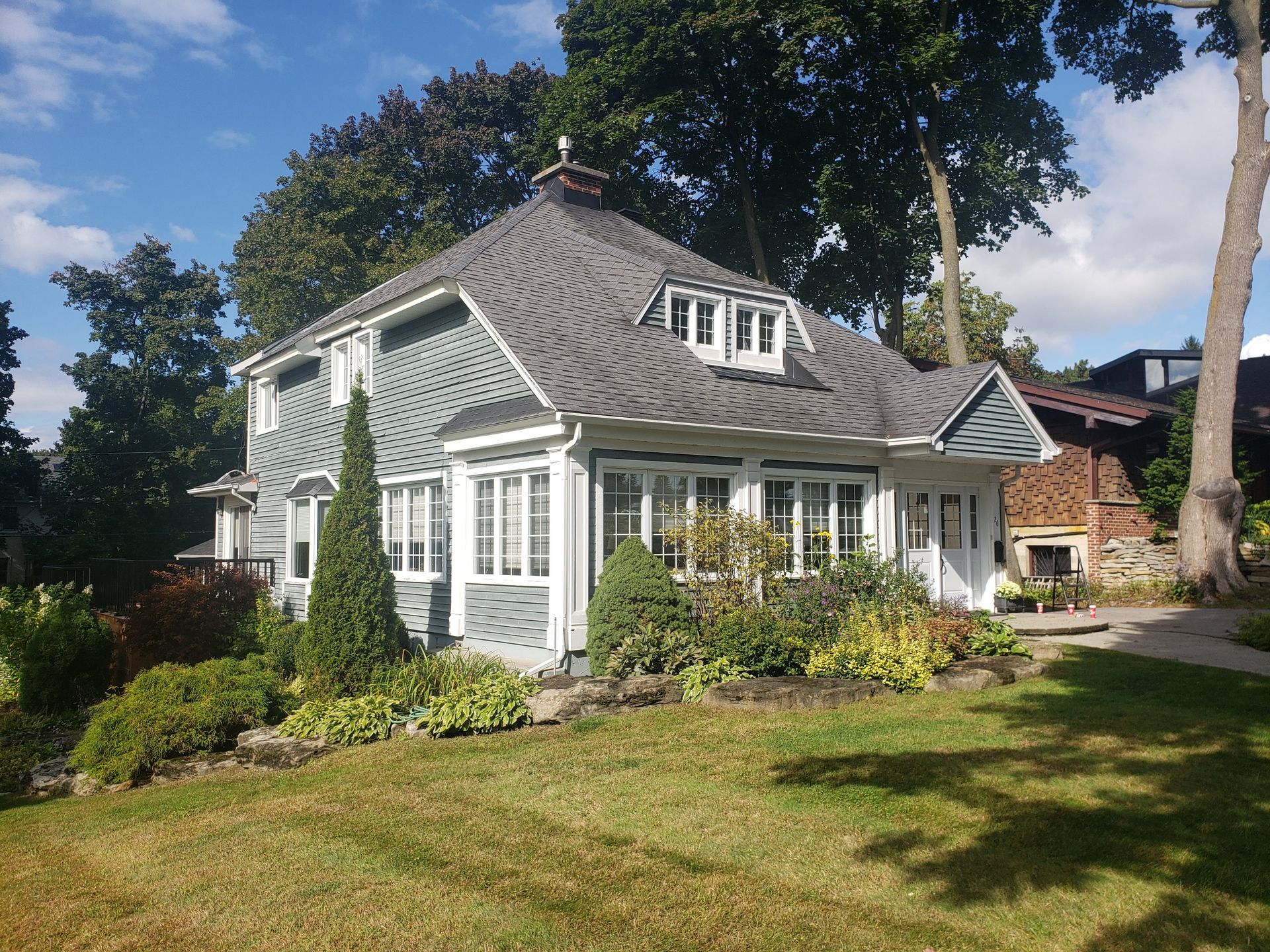 Une maison au toit gris est entourée d'arbres et d'herbe