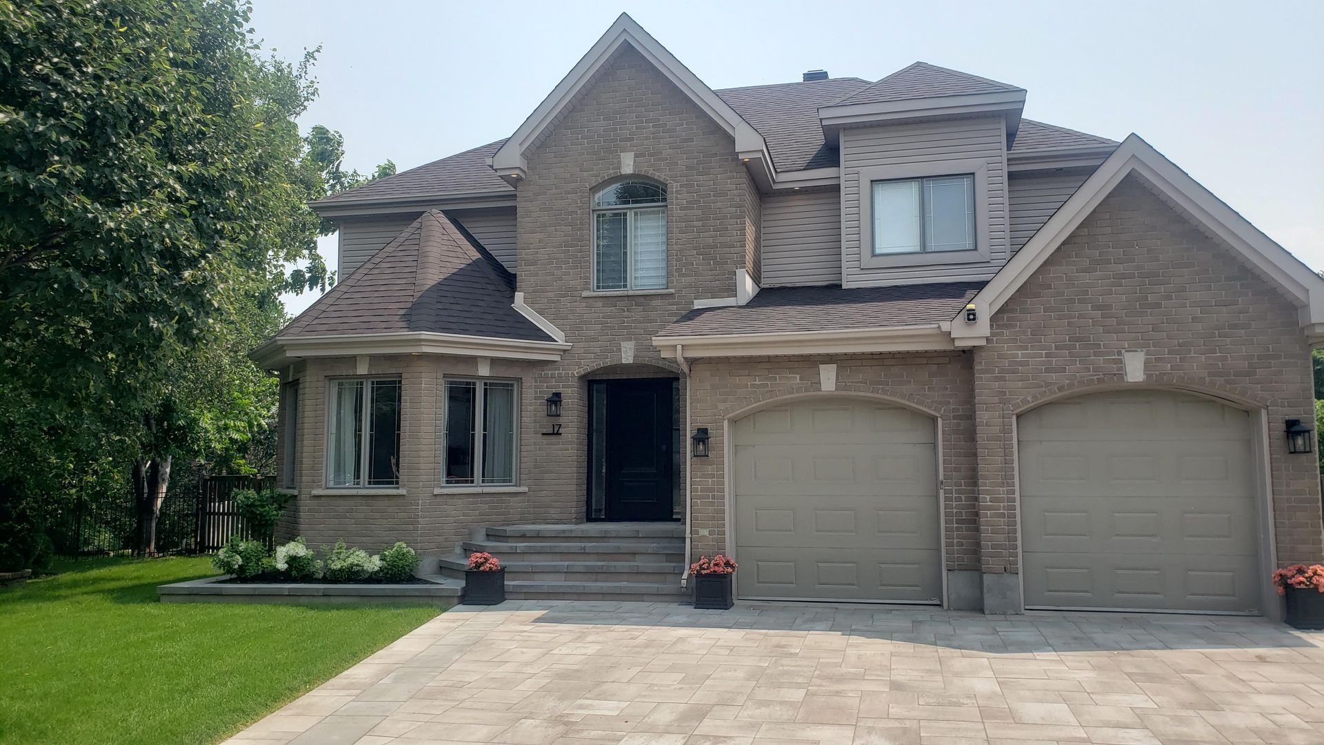 Une grande maison en brique avec trois portes de garage et une allée
