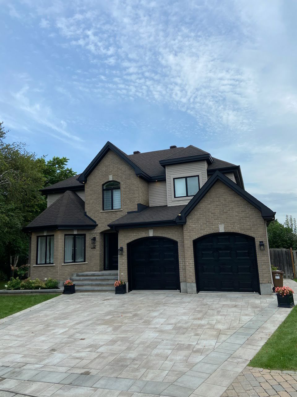 A large brick house with two black garage doors and a driveway.