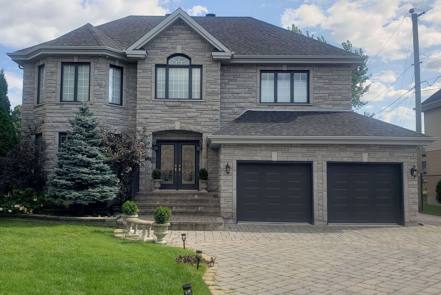 Une grande maison en brique avec deux garages et une allée.