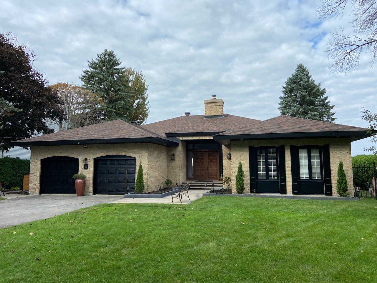 Une grande maison en brique avec deux garages et une grande pelouse devant.
