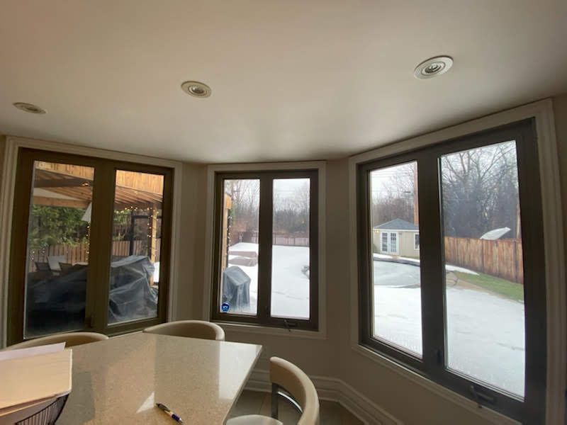 Une pièce avec une table et des chaises et beaucoup de fenêtres