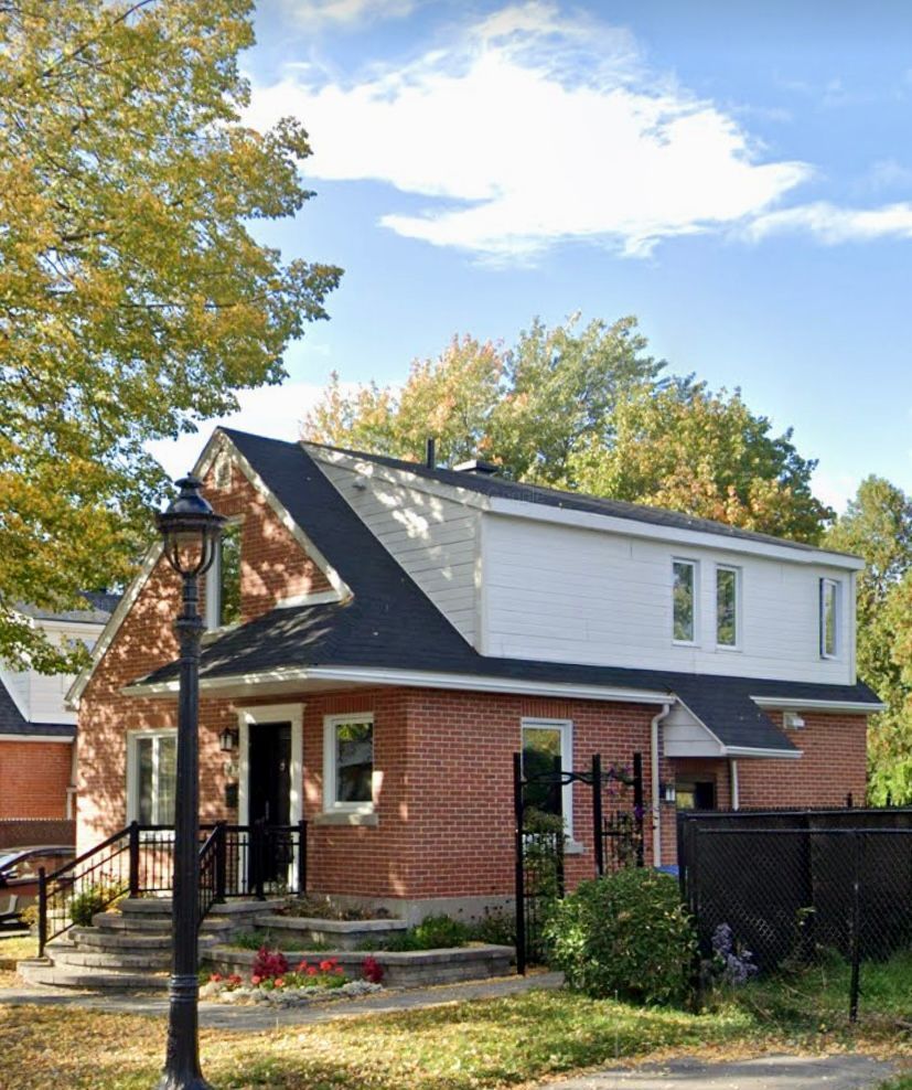 Une maison en brique avec une bordure blanche et un toit noir