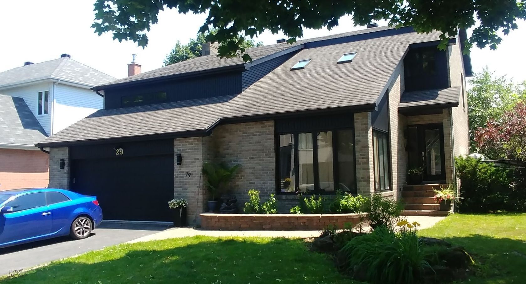 Une voiture bleue est garée devant une maison