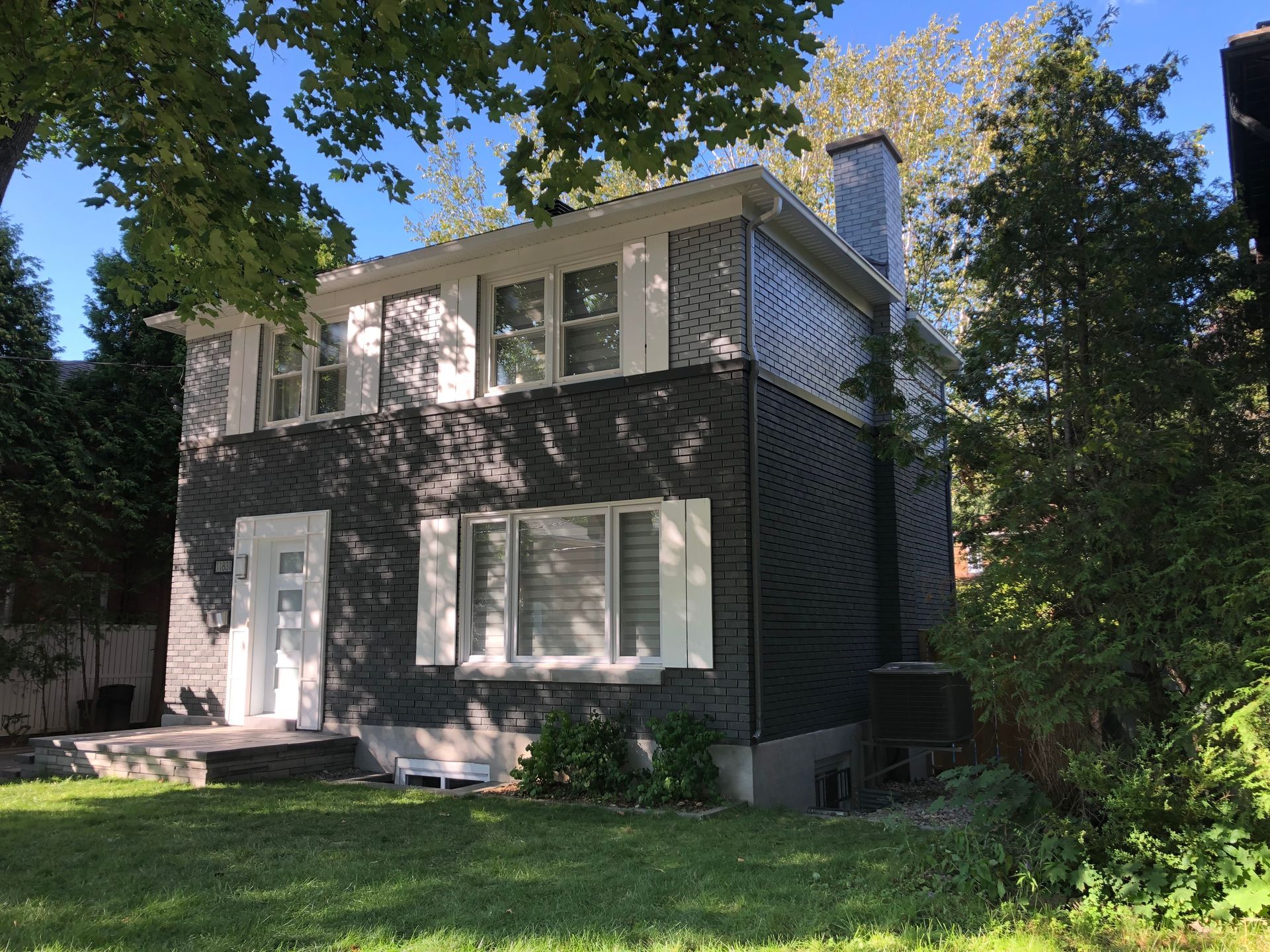 Une grande maison avec beaucoup de fenêtres est entourée d'arbres