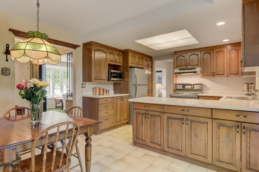 Une cuisine avec armoires en bois et une table et des chaises