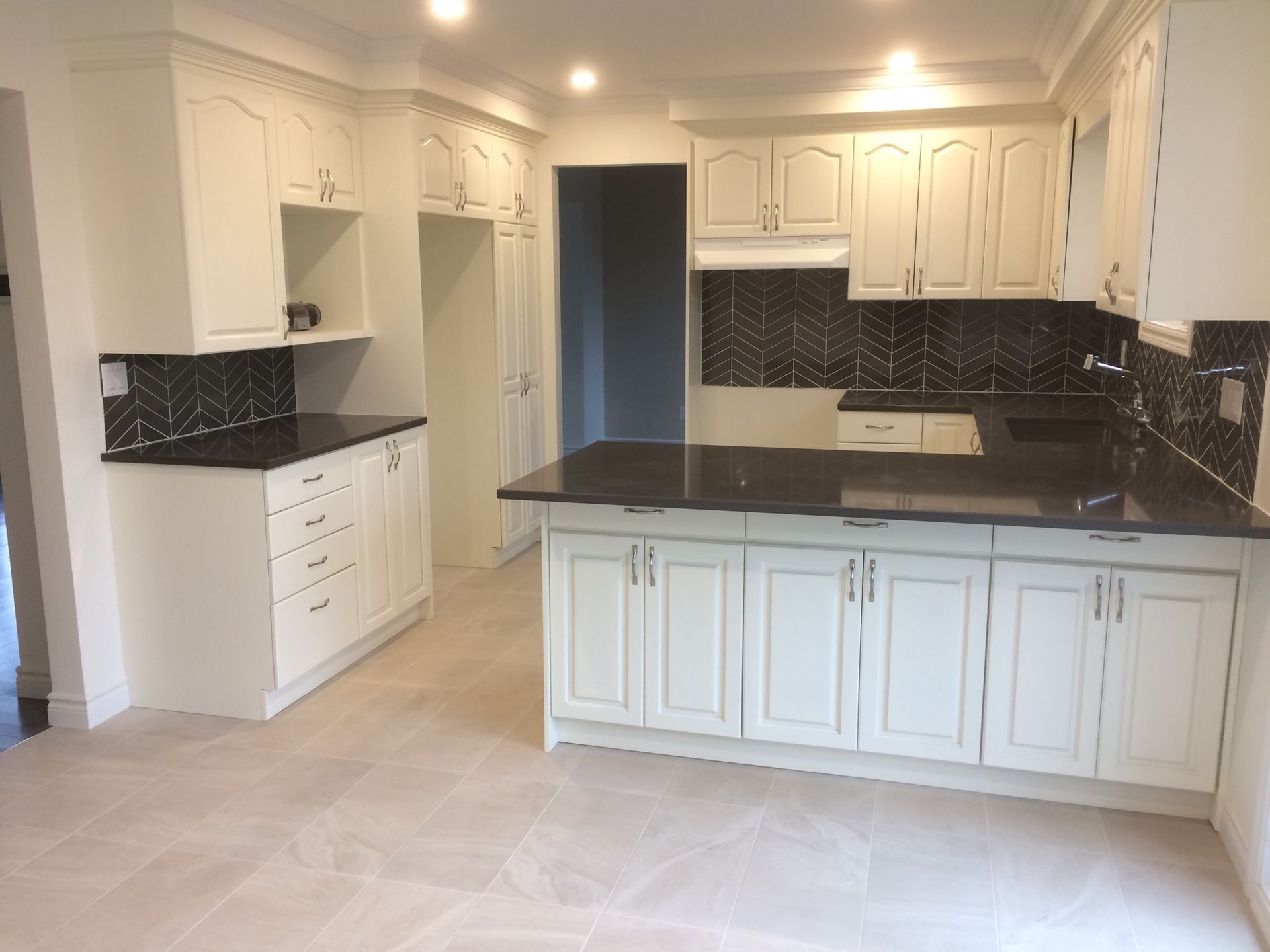 Une cuisine vide avec des armoires blanches et des comptoirs noirs